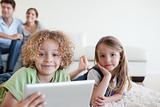 Happy children using a tablet computer while their happy parents are watching