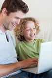 Portrait of a cute boy and his father using a laptop
