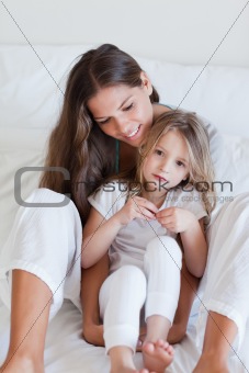 Portrait of a mother and her daughter posing on a bed
