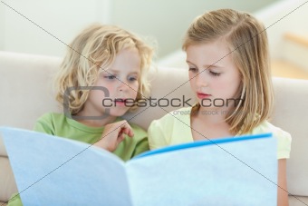 Siblings reading magazine on the couch