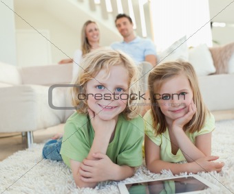 Children on the carpet with tablet and parents behind them