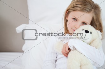Girl with her teddy sitting on the bed