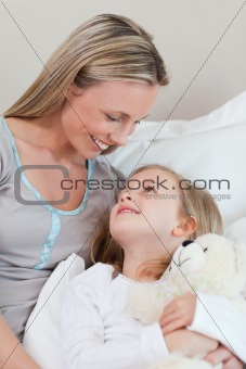 Mother hugging her daughter on the bed