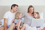 Family using laptop on the bed