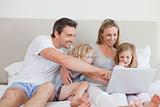 Family using notebook on the bed