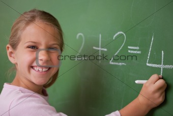 Happy schoolgirl writing a number