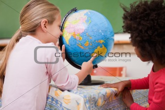 Little schoolgirls looking at a globe