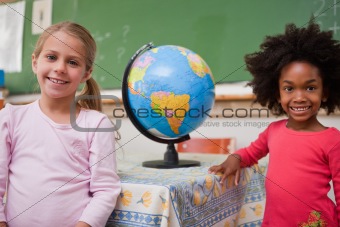 Cute schoolgirls posing with a globe