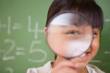 Close up of a cute schoolgirl looking through a magnifying glass
