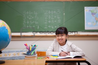 Smiling schoolgirl drawing on a coloring book