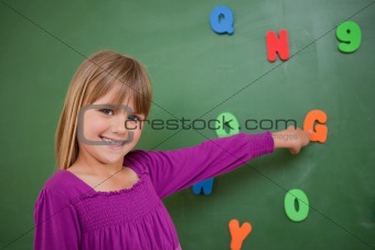 Little schoolgirl pointing at a letter
