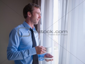 Businessman drinking coffee and looking out of window