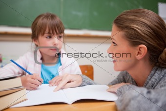 Schoolgirl writing a while her teacher is talking