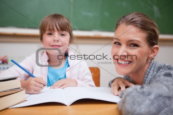 Schoolgirl writing with her teacher