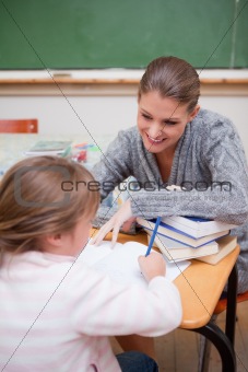 Portrait of a schoolgirl writing with her teacher