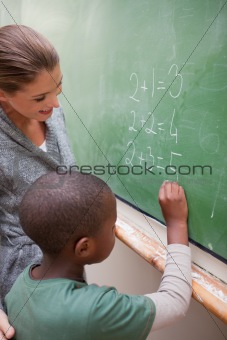 Portrait of a smiling teacher and a pupil making an addition