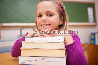 Happy schoolgirl posing with a stack of books