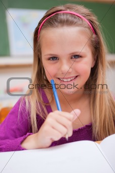 Portrait of a little schoolgirl writing on a book