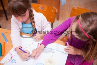 Schoolgirls drawing in a coloring book