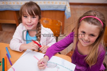 Cute schoolgirls drawing in a coloring book