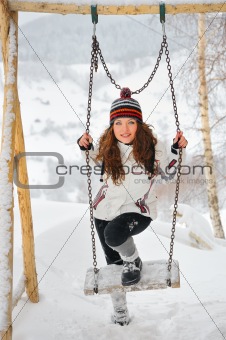 Young Beautiful Woman in winter time and swing