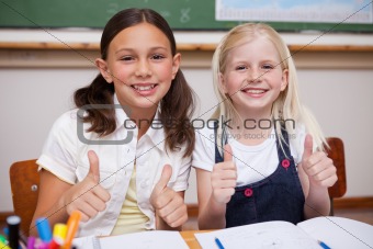 Portrait of happy pupils working together with the thumbs up