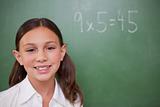 Smiling schoolgirl posing in front of a chalkboard