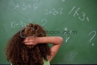 Schoolgirl thinking about mathematics while scratching the back of her head