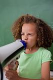Portrait of a schoolgirl screaming through a megaphone