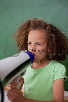 Portrait of a schoolgirl screaming through a megaphone
