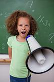 Portrait of a young schoolgirl screaming through a megaphone