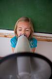 Portrait of an angry schoolgirl screaming through a megaphone