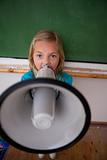 Portrait of an angry schoolgirl yelling through a megaphone