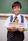 Portrait of a schoolboy holding books and an apple