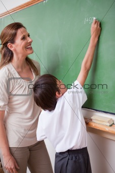Portrait of a schoolteacher helping a schoolboy doing an addition