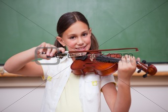 Smiling schoolgirl playing the violin