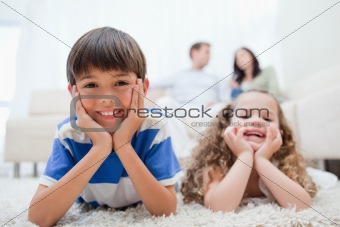 Kids lying on the carpet with parents sitting behind them