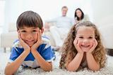 Happy kids lying on the carpet with parents behind them
