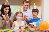 Parents applauding her daughter who just blew out the candles on birthday cake
