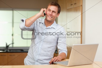 Man with laptop and cellphone in the kitchen