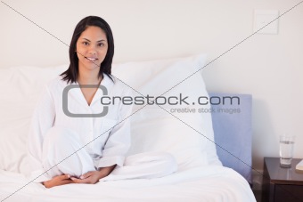 Woman in pajamas sitting on her bed