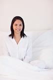 Smiling woman in pajamas sitting on the bed