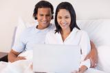 Couple sitting on the bed with their laptop