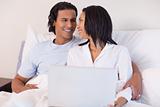 Young couple sitting on the bed with their laptop