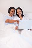Couple sitting on the bed with their notebook