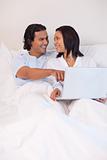 Couple sitting on the bed surfing the internet