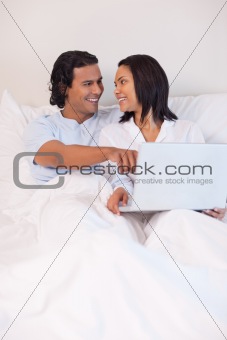 Couple sitting on the bed surfing the internet