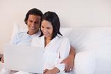 Couple sitting on the bed using the internet