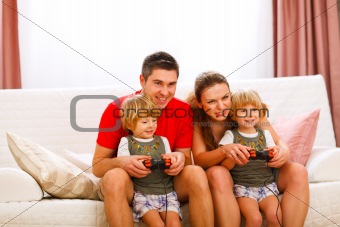 Mother and father playing with twins daughter on console