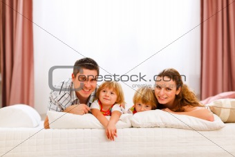 Family portrait of mother father and twins daughters on bed